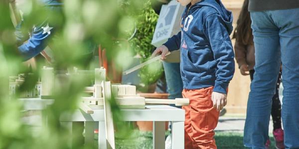 Bambino gioca con costruzioni in legno all'aperto
