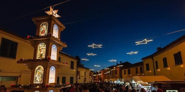 Un mercatino natalizio con luci a forma di stelle, una grande torre decorata e una folla che si gode l'atmosfera festiva sotto il cielo notturno